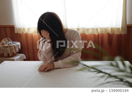 髪も整えず部屋着のまま力なくうつむく女性 髪も整えず部屋着のまま力なくうつむく女性 138900184