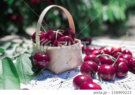 still life of cherries in wicker basket on table in garden still life of cherries in wicker basket on table in garden 138900223
