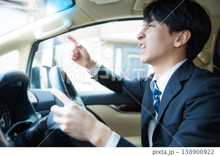 運転中にスマートフォンを見る若いビジネスマン 運転中にスマートフォンを見る若いビジネスマン 138900922