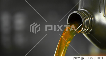 Close-up of motor oil pouring from a plastic container. Golden viscous liquid with bubbles flowing smoothly, automotive maintenance concept with shallow depth of field. 138901091
