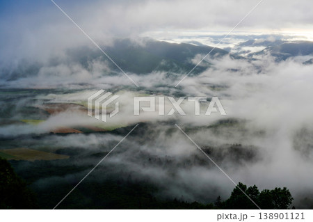 北海道・青空と雲海から顔を出す山頂。山々の間に雲海が広がる幻想的な朝の情景。山間に広がる幻想的な雲海 138901121