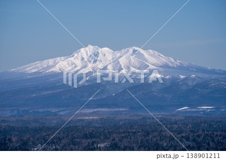 青空のもと雪をまとった雄大な山岳と広大な原始林が広がる北海道の冬の絶景 138901211