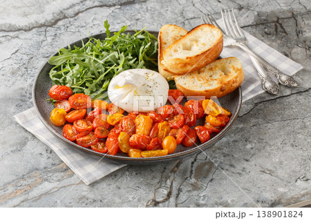 Delicious Italian burrata, baked cherry tomatoes and fresh arugula with olive oil and toasted ciabatta close-up in a plate. Horizontal Delicious Italian burrata, baked cherry tomatoes and fresh arugula with olive oil and toasted ciabatta close-up in a plate. Horizontal 138901824