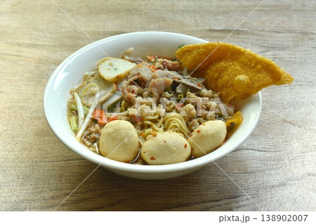 Chinese egg yellow noodles topping chop pork and meatball with crispy fried dumpling paste in spicy tom yum soup on bowl Chinese egg yellow noodles topping chop pork and meatball with crispy fried dumpling paste in spicy tom yum soup on bowl 138902007