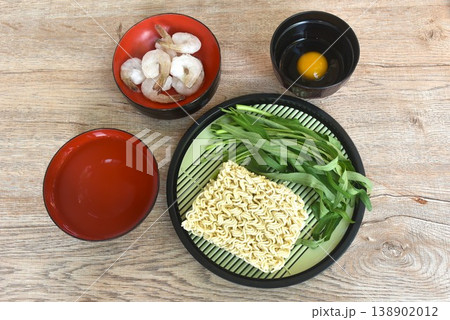 instant noodles with frozen shrimp and morning glory couple raw egg in water on bowl 138902012