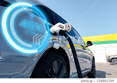 Electric car reaches 48 percent charge while connected to charging station in bright daylight 138902104