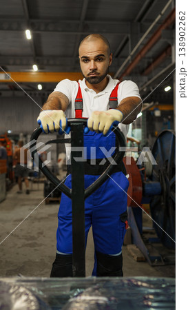 Worker moving equipment in warehouse using pallet jack during day shift Worker moving equipment in warehouse using pallet jack during day shift 138902262