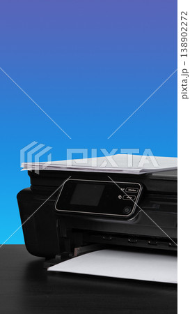 Printer with paper on a table against a blue background during daylight Printer with paper on a table against a blue background during daylight 138902272