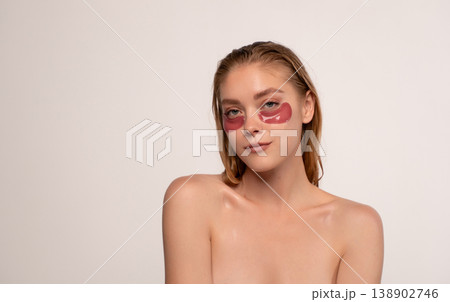 Young woman applying red hydrogel eye patches for under eye skincare, moisturizing and reducing puffiness Young woman applying red hydrogel eye patches for under eye skincare, moisturizing and reducing puffiness 138902746