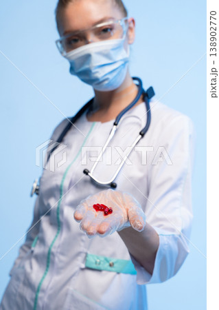 Healthcare professional wearing protective gear offering red pills for treatment, prevention, and medicine Healthcare professional wearing protective gear offering red pills for treatment, prevention, and medicine 138902770