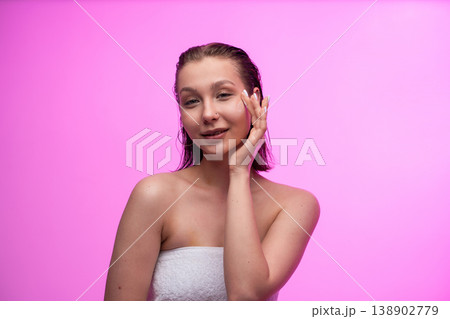 Young woman applying nourishing face cream for hydrated, clean skin on a pink background, embracing a healthy beauty routine and self-care for wellness Young woman applying nourishing face cream for hydrated, clean skin on a pink background, embracing a healthy beauty routine and self-care for wellness 138902779