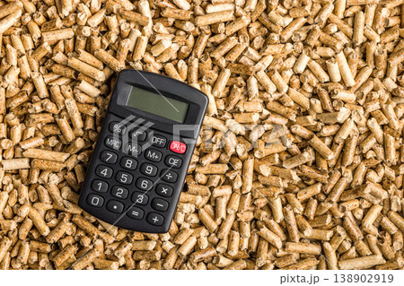 Calculator and Wood Pellets Representing Biomass Fuel Cost, Renewable Energy Budget and Home Heating Expenses Calculator and Wood Pellets Representing Biomass Fuel Cost, Renewable Energy Budget and Home Heating Expenses 138902919
