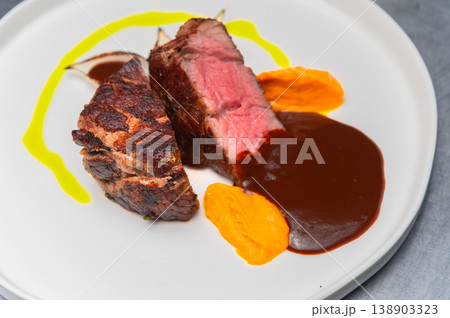 Grilled beef steak served with sauce and colorful vegetable puree on plate 138903323