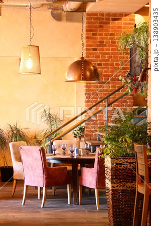 Illuminated eating area with plush seating and lush greenery ambience 138903435