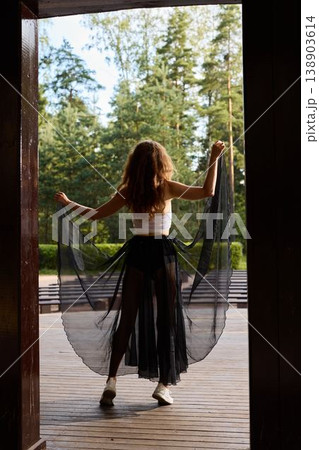 Calm dancer commences morning with soft gestures beneath pine branches Calm dancer commences morning with soft gestures beneath pine branches 138903614