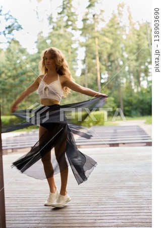 Chic female engages in serene dance amid lively surroundings Chic female engages in serene dance amid lively surroundings 138903690