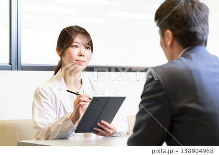 タブレットを手に社員の話を真剣に聞く産業医の女性 タブレットを手に社員の話を真剣に聞く産業医の女性 138904968