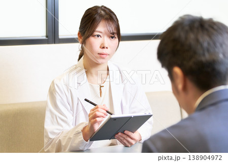 タブレットを手に社員の話を真剣に聞く産業医の女性 タブレットを手に社員の話を真剣に聞く産業医の女性 138904972