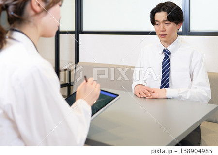 産業医の個別面談で悩みや体調不良を相談する若手社員の男性 138904985