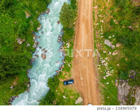 Car parked neat a dirt road and river in mountainous Kyrgyzstan, drone view from above Car parked neat a dirt road and river in mountainous Kyrgyzstan, drone view from above 138905079