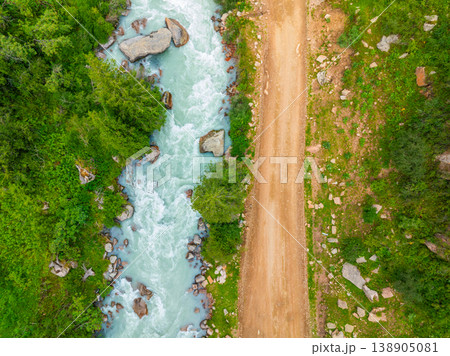 Mountain river flowing through green rocky terrain near dirt road in Kyrgyzstan Mountain river flowing through green rocky terrain near dirt road in Kyrgyzstan 138905081