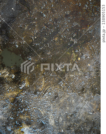 Close-up of dark oily puddles with reflective droplets 138905153