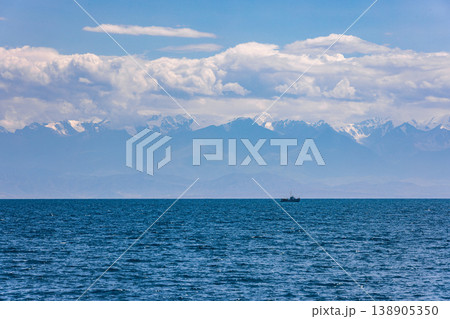 Boat sailing on serene water with mountains in background 138905350