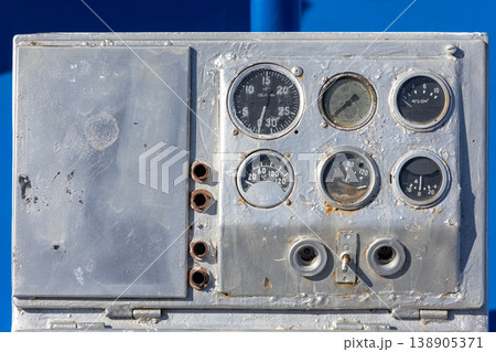 Old boat control panel with analog gauges in industrial setting 138905371
