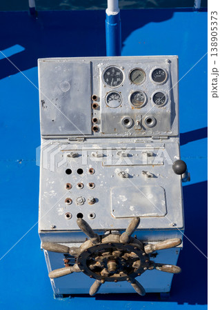 Control panel with steering wheel and gauges on ship deck 138905373