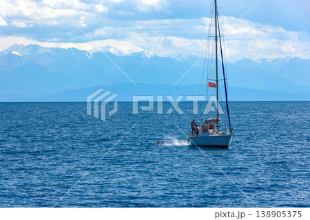 People swimming near sailboat in Kyrgyzstan waters of Issyk-Kul lake People swimming near sailboat in Kyrgyzstan waters of Issyk-Kul lake 138905375