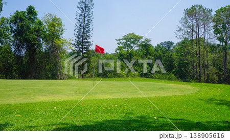 Green grass and woods on a golf field. View of Golf Course with beautiful putting green. Green grass and woods on a golf field. View of Golf Course with beautiful putting green. 138905616