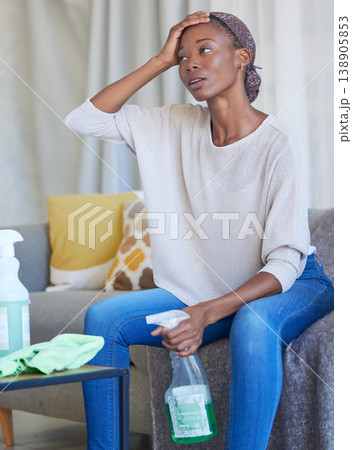 House cleaning, black woman and tired person in a living room with stress and anxiety from home work. Dust, cleaner and maid service of a young female with dust spray and housekeeping wash product House cleaning, black woman and tired person in a living room with stress and anxiety from home work. Dust, cleaner and maid service of a young female with dust spray and housekeeping wash product 138905853