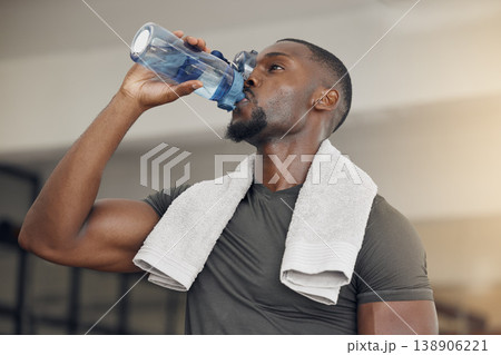 Fitness, gym and black man drinking water after workout or training for hydration, health or wellness. Strong, healthy and African athlete enjoying a beverage after intense exercise at sports center. Fitness, gym and black man drinking water after workout or training for hydration, health or wellness. Strong, healthy and African athlete enjoying a beverage after intense exercise at sports center. 138906221