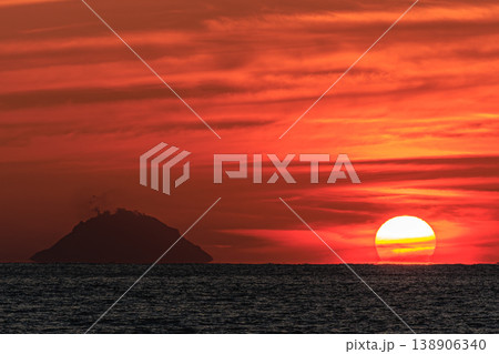 種子島の水平線に沈む夕日と島影 138906340