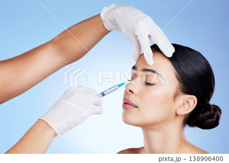 Plastic surgery, face and surgeon injection for beauty, filler and change for a woman in studio. Aesthetic model and doctor hands for cosmetic surgery, transformation or dermatology blue background Plastic surgery, face and surgeon injection for beauty, filler and change for a woman in studio. Aesthetic model and doctor hands for cosmetic surgery, transformation or dermatology blue background 138906400