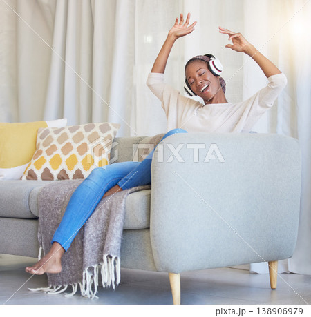 Black woman, headphones and happy on couch, for dancing and listening to music in living room with smile. Headset, African American girl and female streaming audio, radio and on sofa for happiness. 138906979