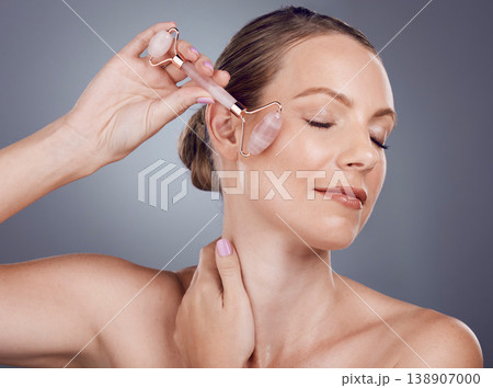 Woman, face roller and beauty of facial product of aesthetic skincare massage in studio. Female model, rose quartz treatment and wellness for natural cosmetics, crystal stone dermatology or salon spa Woman, face roller and beauty of facial product of aesthetic skincare massage in studio. Female model, rose quartz treatment and wellness for natural cosmetics, crystal stone dermatology or salon spa 138907000