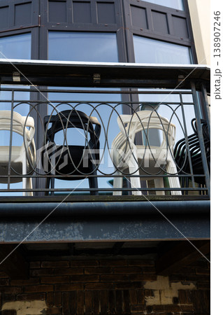 plastic chairs are folded and stand on the balcony behind the fence plastic chairs are folded and stand on the balcony behind the fence 138907246
