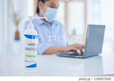 Hand sanitizer, covid and business woman typing on a laptop at desk in her office with face mask. Hygiene, technology and professional employee working on project with computer during corona pandemic 138907800