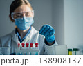 Laboratory professional wearing safety equipment analyzes test tubes with colorful liquids in bright research facility. Medical science, innovation are highlighted in this clinical laboratory setting 138908137