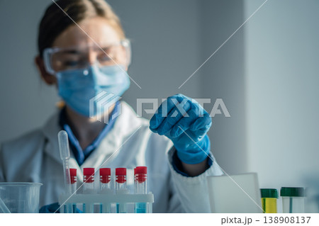 Laboratory professional wearing safety equipment analyzes test tubes with colorful liquids in bright research facility. Medical science, innovation are highlighted in this clinical laboratory setting Laboratory professional wearing safety equipment analyzes test tubes with colorful liquids in bright research facility. Medical science, innovation are highlighted in this clinical laboratory setting 138908137