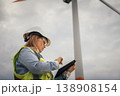 A qualified female engineer in safety gear inspects a wind turbine with a tablet, showcasing the link between technology and sustainable renewable energy practices vital for our future 138908154