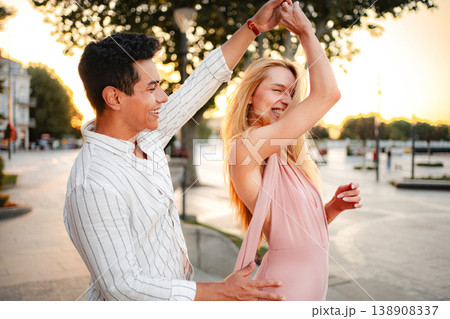 Couple dances joyfully in the sunset on a charming city street Couple dances joyfully in the sunset on a charming city street 138908337