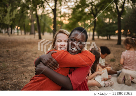 Two cheerful female teachers hugging each other in a park Two cheerful female teachers hugging each other in a park 138908362