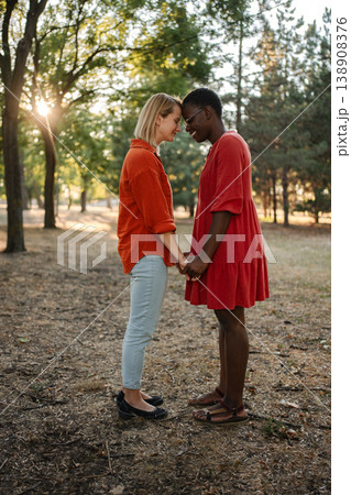 Two Young Women Holding Hands and Touching Foreheads in a Park Two Young Women Holding Hands and Touching Foreheads in a Park 138908376