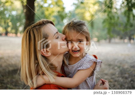 Mother comforting her crying daughter in a park Mother comforting her crying daughter in a park 138908379