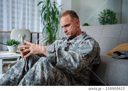 Depressed soldier sitting on floor suffering from post traumatic stress disorder 138908423