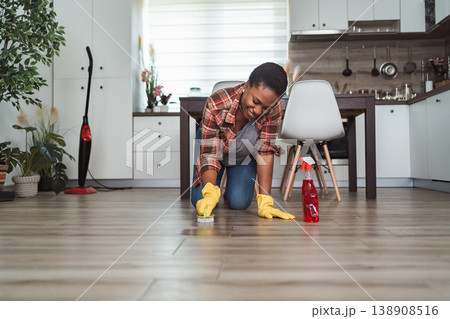 Young woman scrubbing kitchen floor enjoying housework wearing yellow gloves Young woman scrubbing kitchen floor enjoying housework wearing yellow gloves 138908516