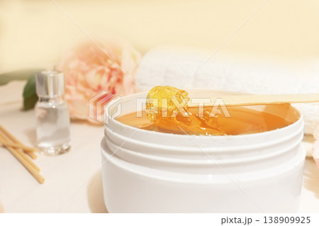 Liquid yellow paste for shugaring on a wooden stick, close-up. Liquid yellow paste for shugaring on a wooden stick, close-up. 138909925