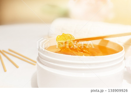 Liquid yellow paste for shugaring on a wooden stick, close-up. Liquid yellow paste for shugaring on a wooden stick, close-up. 138909926